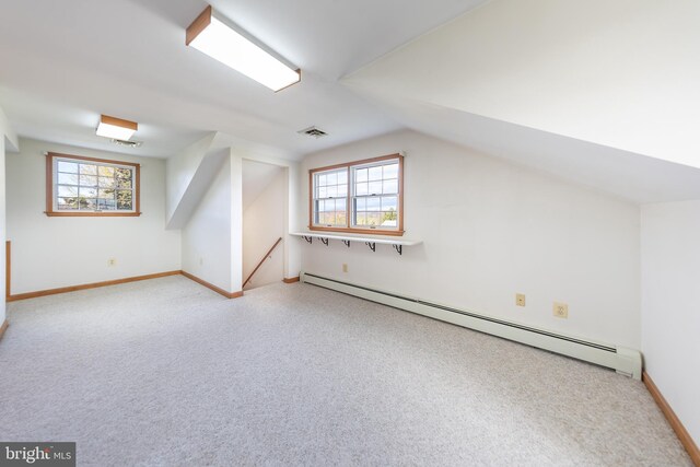 additional living space with baseboards, a baseboard heating unit, a healthy amount of sunlight, and vaulted ceiling