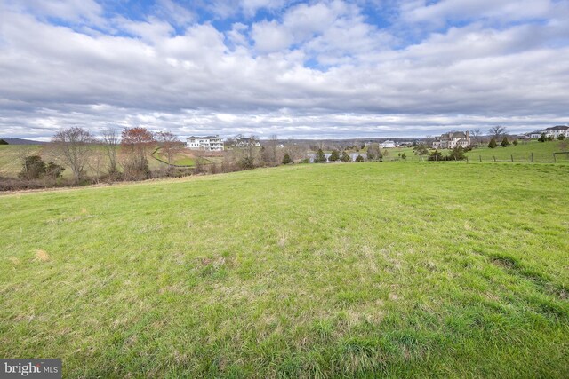 view of yard with fence and a rural view