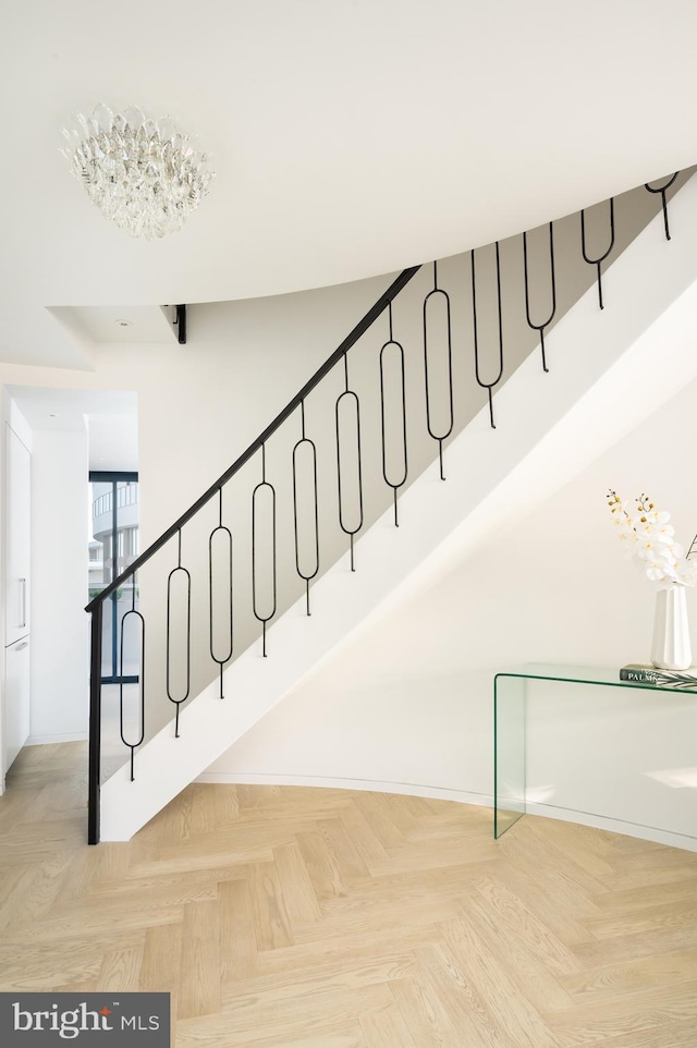 stairs with a notable chandelier and light parquet flooring