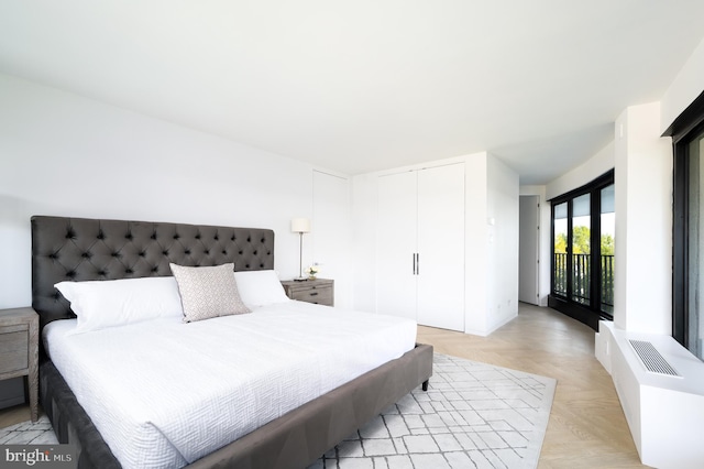 bedroom with light parquet floors, access to exterior, and a closet