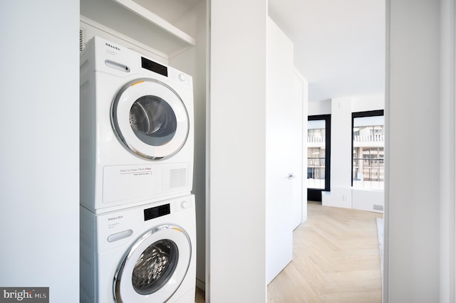 laundry area with stacked washing maching and dryer and light parquet flooring