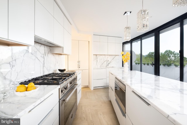 kitchen featuring appliances with stainless steel finishes, light parquet flooring, tasteful backsplash, and white cabinetry