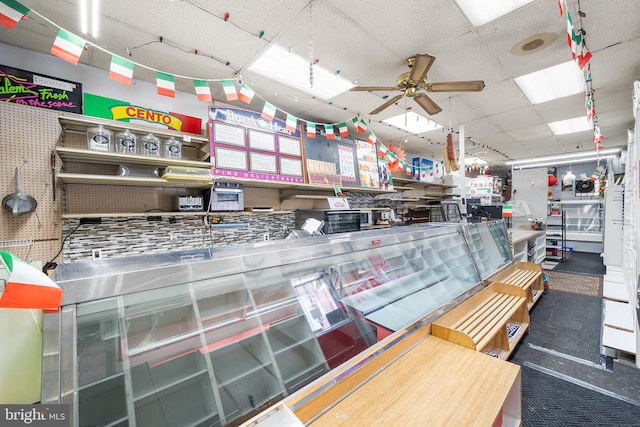 interior space featuring ceiling fan and a drop ceiling