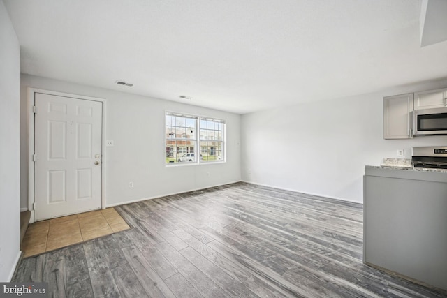 interior space with light stone countertops, stove, gray cabinetry, and dark wood-type flooring