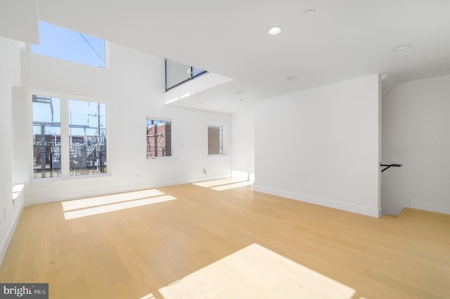 unfurnished living room with light hardwood / wood-style flooring and a high ceiling