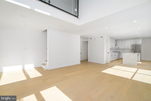 unfurnished living room with light hardwood / wood-style flooring and sink