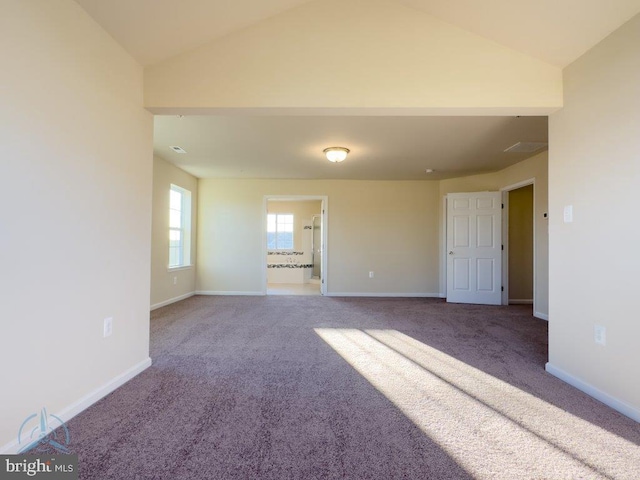 unfurnished room with vaulted ceiling and dark carpet