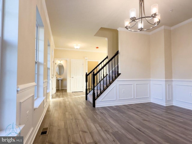 foyer featuring ornamental molding, wood-type flooring, and a chandelier