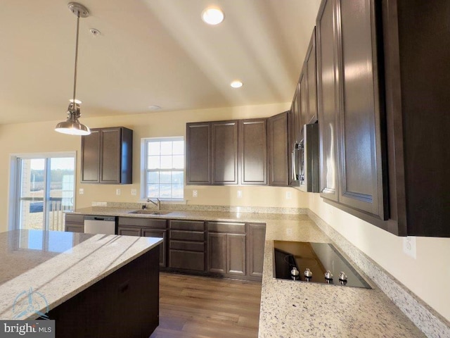 kitchen featuring hardwood / wood-style floors, appliances with stainless steel finishes, sink, light stone counters, and lofted ceiling