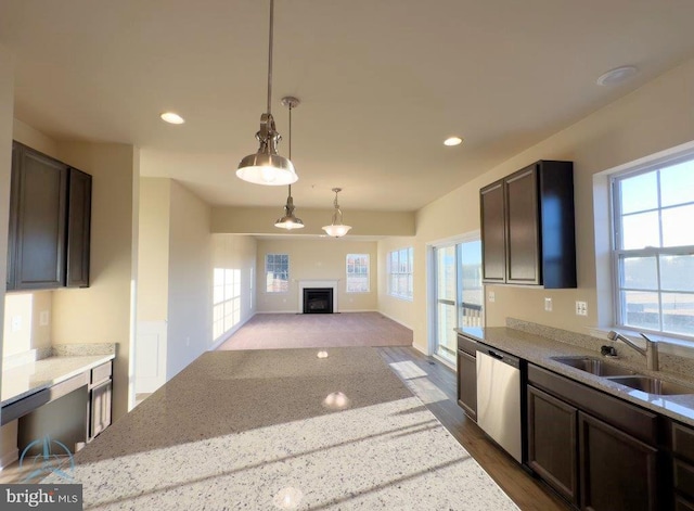 kitchen with dark brown cabinets, light stone countertops, sink, pendant lighting, and stainless steel dishwasher