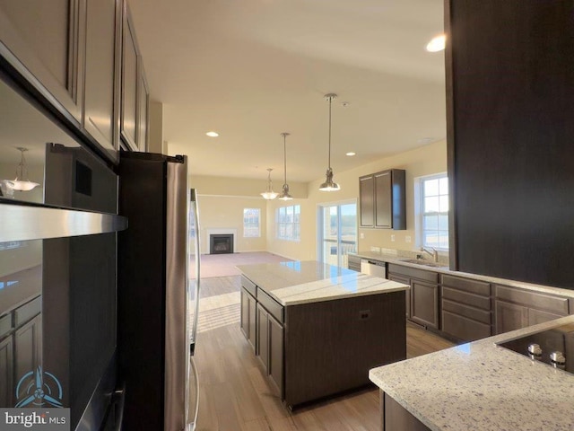 kitchen with light hardwood / wood-style floors, stainless steel appliances, a kitchen island, and a wealth of natural light