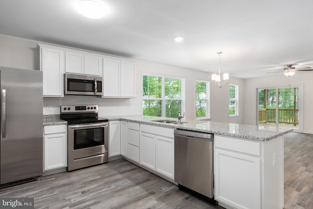 kitchen with appliances with stainless steel finishes, sink, hardwood / wood-style floors, and white cabinets