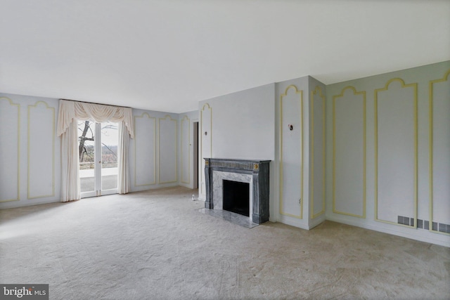 unfurnished living room with a premium fireplace and light colored carpet