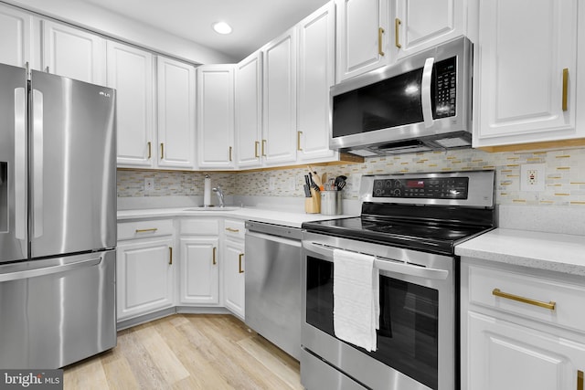 kitchen featuring white cabinets, sink, decorative backsplash, appliances with stainless steel finishes, and light hardwood / wood-style floors