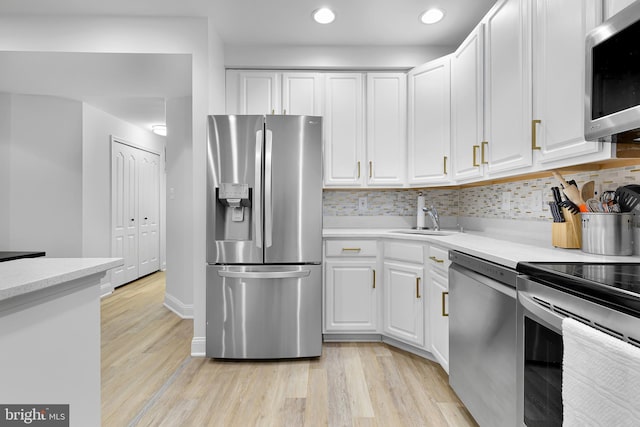 kitchen with white cabinetry, sink, light hardwood / wood-style flooring, decorative backsplash, and appliances with stainless steel finishes