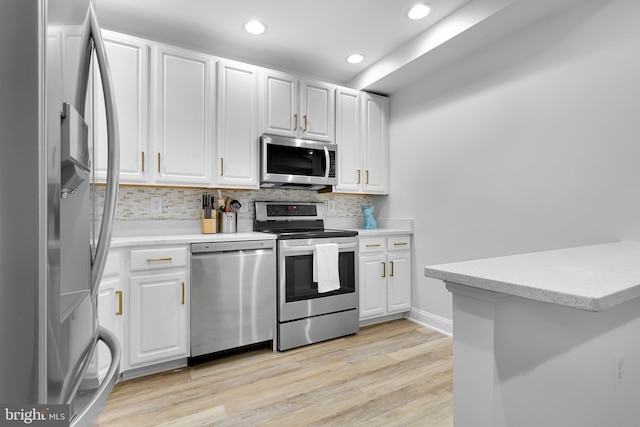 kitchen with decorative backsplash, appliances with stainless steel finishes, kitchen peninsula, light hardwood / wood-style flooring, and white cabinets