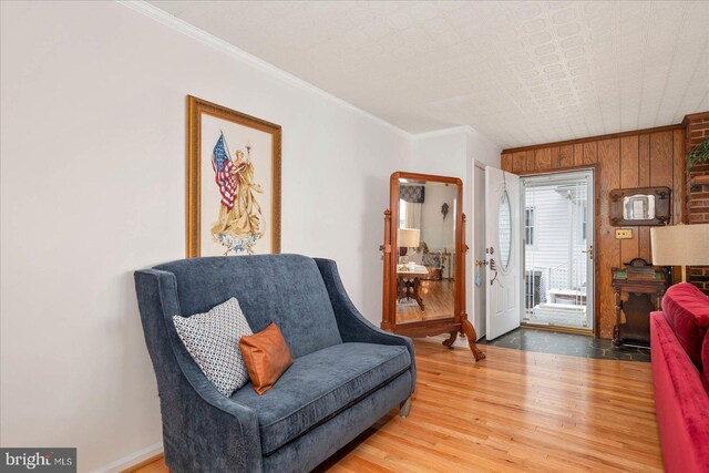 sitting room featuring crown molding, wood walls, and hardwood / wood-style flooring