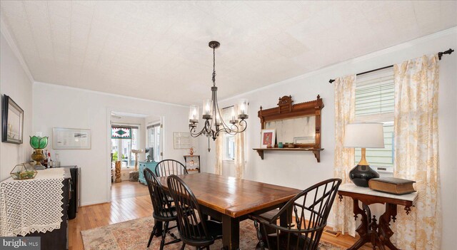 dining room featuring crown molding, an inviting chandelier, and hardwood / wood-style floors