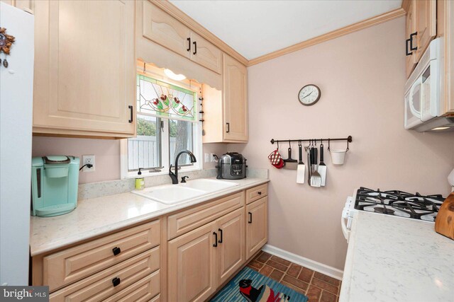 kitchen with light brown cabinetry, white appliances, crown molding, dark tile floors, and sink