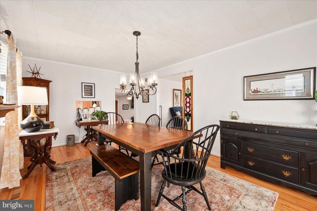 dining room featuring light hardwood / wood-style flooring, crown molding, and a notable chandelier