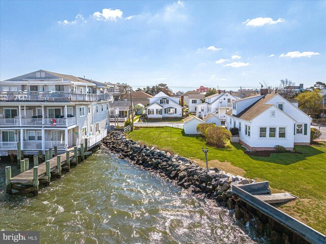 dock area featuring a balcony, a water view, and a lawn