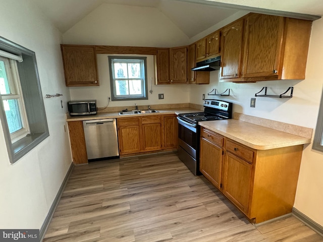 kitchen with appliances with stainless steel finishes, light hardwood / wood-style flooring, sink, and lofted ceiling