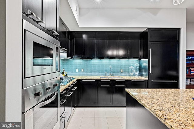 kitchen with appliances with stainless steel finishes, tasteful backsplash, light tile floors, and light stone countertops