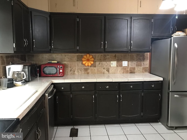 kitchen featuring tasteful backsplash, appliances with stainless steel finishes, and light tile floors