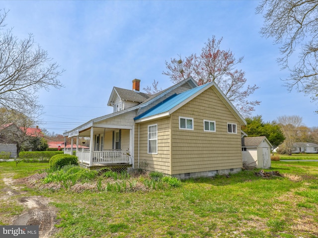 view of side of home featuring a yard, a storage shed, and covered porch