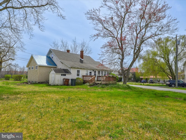 view of front of property featuring a deck, a shed, and a front yard