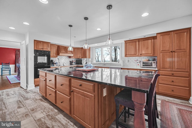 kitchen featuring dark stone countertops, a center island, hanging light fixtures, and backsplash