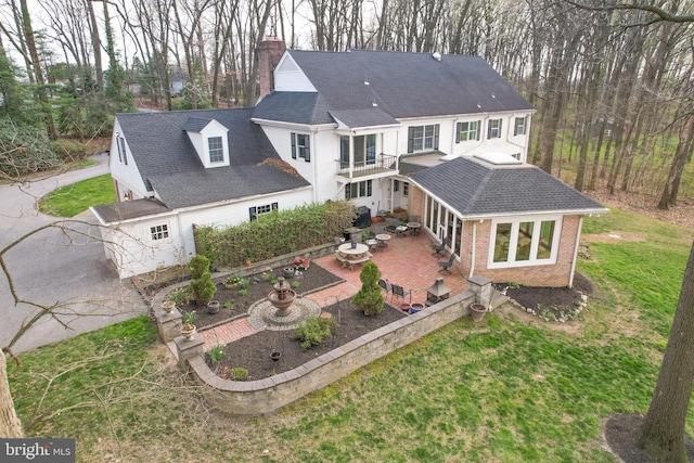 rear view of property with a patio, a yard, and a balcony