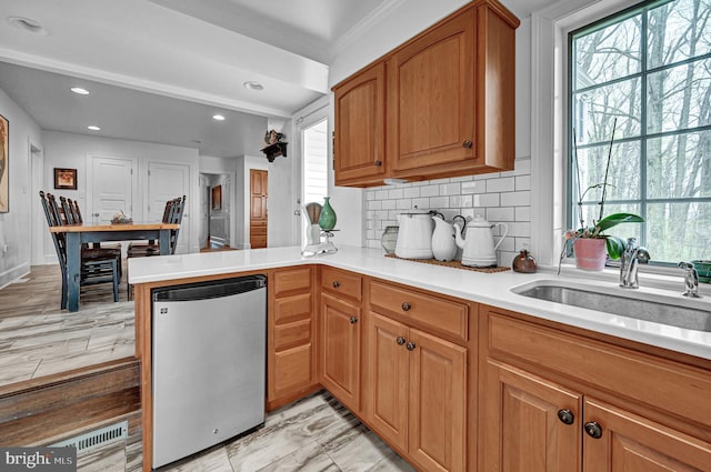 kitchen with kitchen peninsula, stainless steel fridge, backsplash, light hardwood / wood-style flooring, and sink