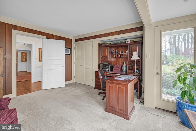 office featuring light carpet, wood walls, ornamental molding, and beam ceiling