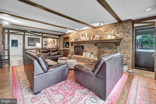 living room featuring beam ceiling, light hardwood / wood-style flooring, and a fireplace