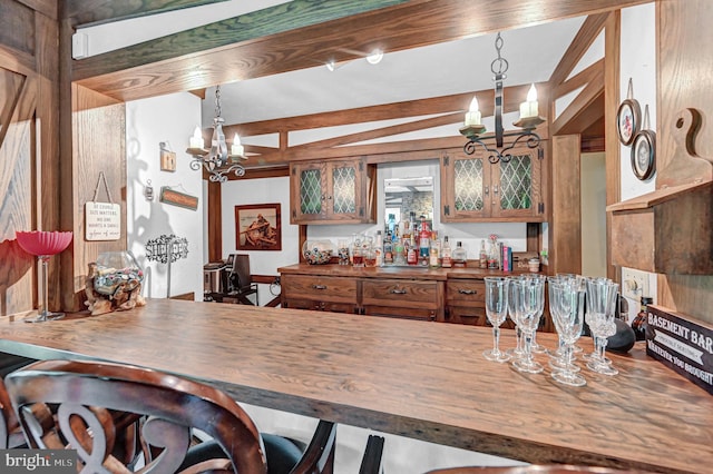 dining area with a notable chandelier, vaulted ceiling, and bar area