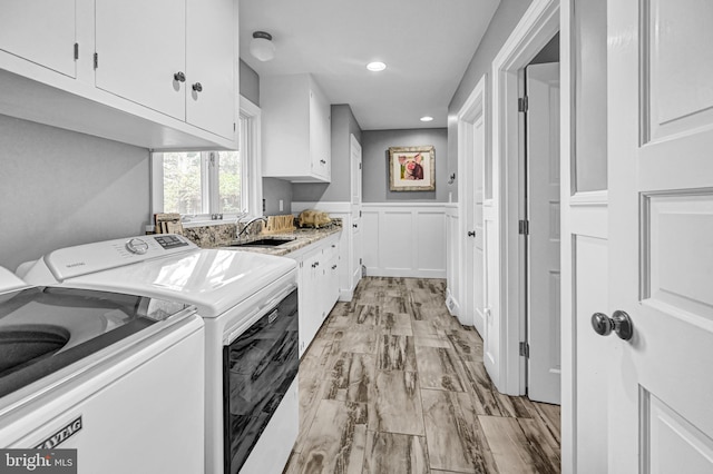 washroom with sink, light wood-type flooring, separate washer and dryer, and cabinets