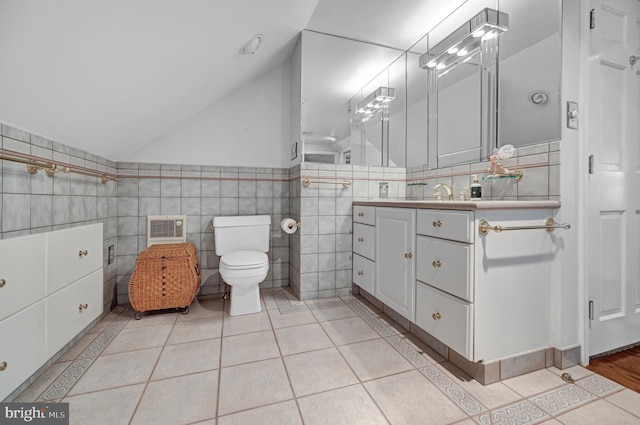 bathroom with lofted ceiling, tile walls, toilet, vanity, and tile patterned floors