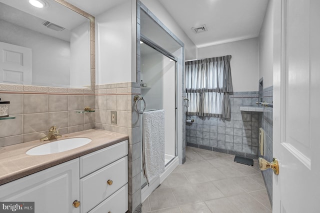 bathroom with vanity, walk in shower, tile patterned floors, and tile walls