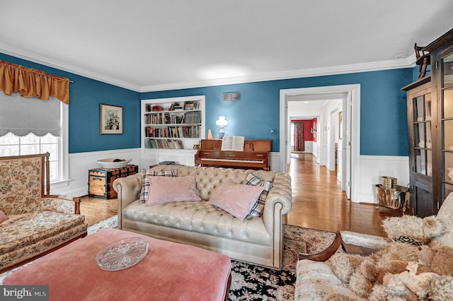 living room with crown molding, built in shelves, and hardwood / wood-style floors