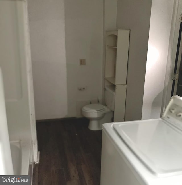 bathroom with a washtub, wood-type flooring, toilet, and washer / clothes dryer