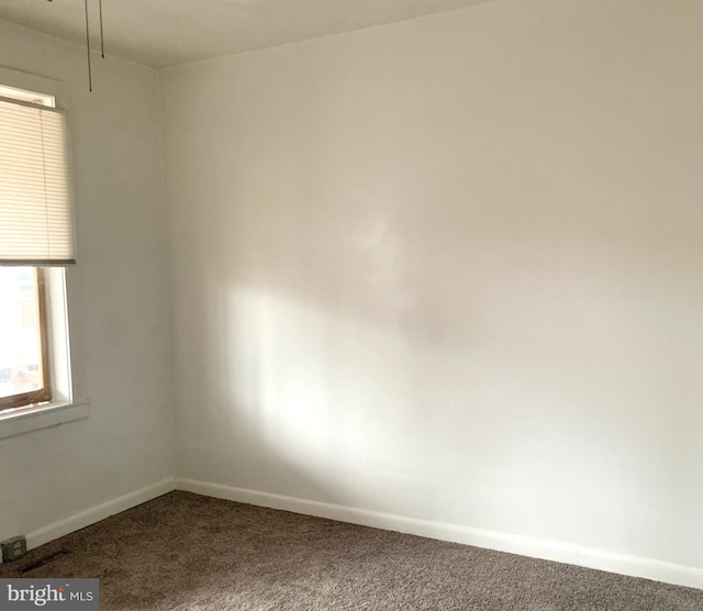 unfurnished room featuring dark colored carpet