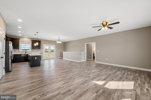 unfurnished living room with light wood-type flooring, baseboards, a sink, and recessed lighting