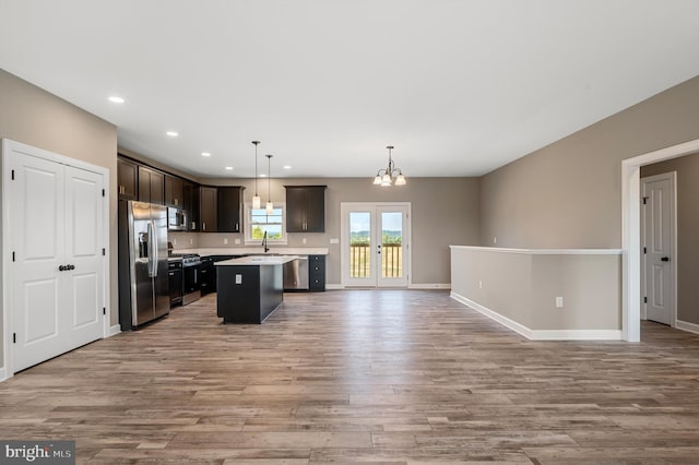 kitchen with a kitchen island, open floor plan, light countertops, appliances with stainless steel finishes, and hanging light fixtures