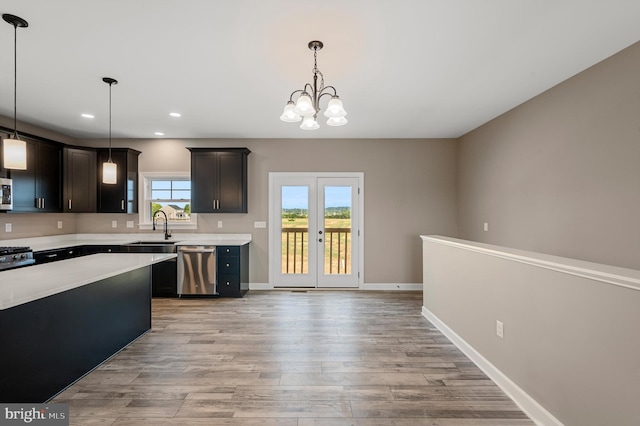 kitchen featuring pendant lighting, light countertops, appliances with stainless steel finishes, dark brown cabinetry, and a sink