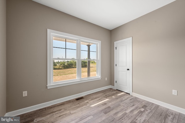 empty room featuring light wood-style floors, baseboards, and visible vents