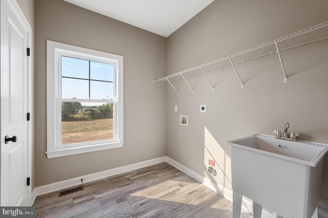 laundry area featuring hookup for an electric dryer, laundry area, visible vents, baseboards, and light wood-style floors