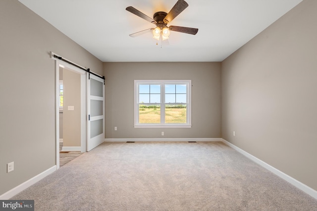 unfurnished bedroom featuring multiple windows, baseboards, and a barn door