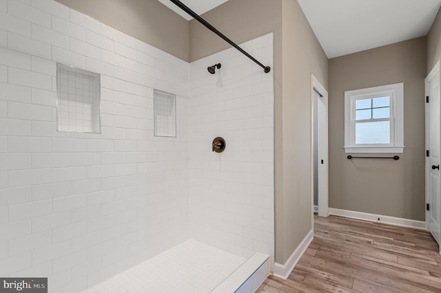 bathroom featuring a stall shower, baseboards, and wood finished floors