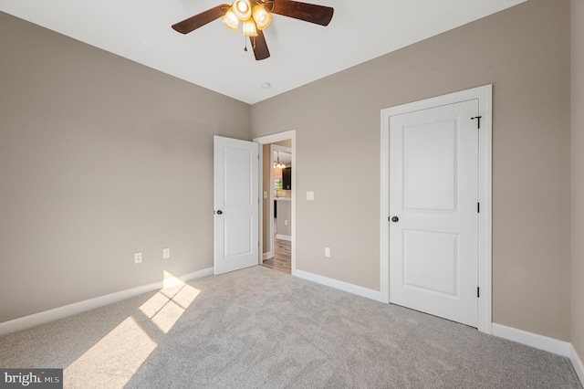 unfurnished bedroom featuring light carpet, ceiling fan, and baseboards